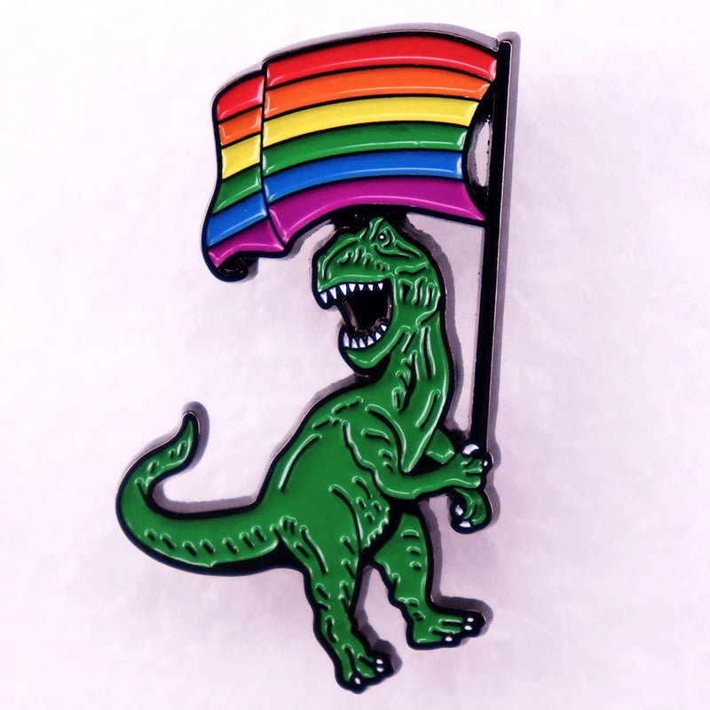 Ein glaenzender Ansteck-Pin mit einem gruenen Dinosaurier, der eine bunte Regenbogenfahne hochhaelt. Ein lebendiges Symbol für Vielfalt und Inklusion.