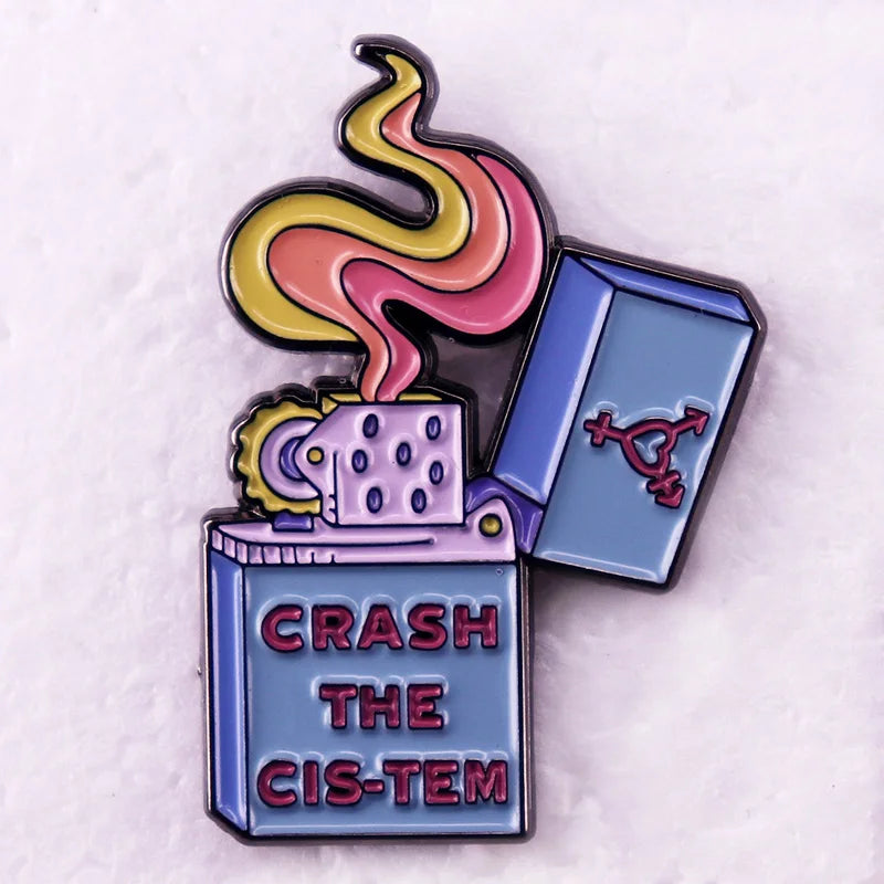 Ein Ansteck-Pin in Form eines offenen Feuerzeugs mit einer stilisierten Flamme. Auf dem Feuerzeug steht der Schriftzug "CRASH THE CIS-TEM", und der Deckel zeigt ein feministisches Symbol.