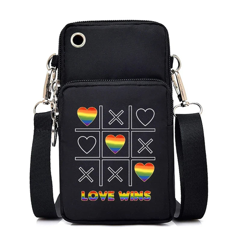 Praktische schwarze Umhängetasche mit einzigartigem Tic-Tac-Toe-Design aus Regenbogenherzen und der Botschaft ‚Love Wins‘. Ausgestattet mit verstellbarem Schultergurt und mehreren Fächern, ideal für den Alltag und Pride-Events