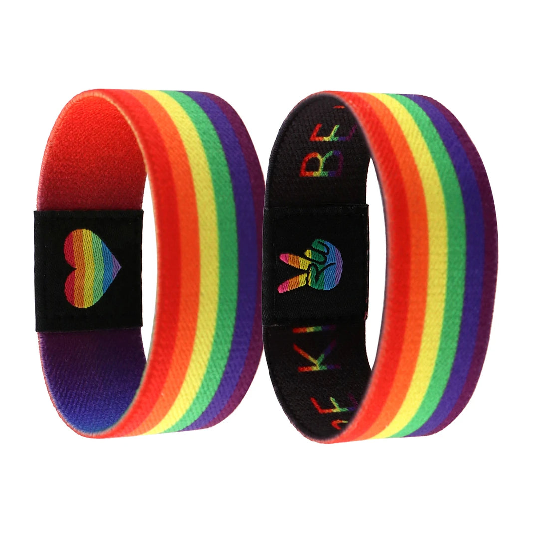 Elastisches Regenbogen Armband. Zwei Ausfuehrungen, einmal im Regenbogen Style und Herz, einmal mit dem Slogan Be Kind auf der Aussenseite.