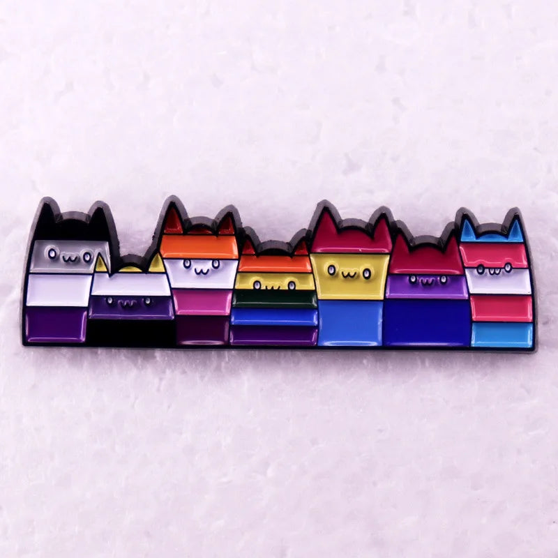 Reihe von Ansteckpins in Form kleiner Katzenfiguren, die jeweils die Farben verschiedener LGBTQ-plus -Pride-Flaggen tragen, darunter Lesben-, Bisexuellen-, Pansexuellen-, Nicht-binaeren-, Asexuellen- und Transgender-Flaggen. Die Katzen haben niedliche Gesichter und spitze Ohren, wodurch sie ein froehliches, verspieltes Aussehen erhalten.