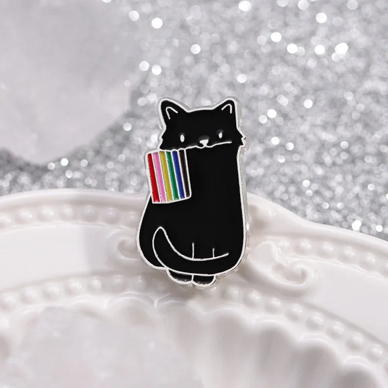 Dieser einzigartige Pin zeigt eine schwarze Katze, die stolz eine LGBTQI+-Regenbogenflagge im Mund traegt. Das Design vereint die kraftvolle Symbolik der Regenbogenflagge mit der geheimnisvollen Eleganz der Katze, wodurch ein ausdrucksstarkes Accessoire entsteht. Perfekt, um an Jacken, Taschen oder Rucksaecken ein Statement für Vielfalt und Akzeptanz zu setzen!