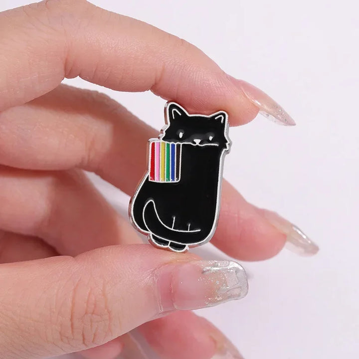 Dieser einzigartige Pin zeigt eine schwarze und eine weisse Katze, die stolz eine LGBTQI+-Regenbogenflagge im Mund tragen. Das Design vereint die kraftvolle Symbolik der Regenbogenflagge mit der geheimnisvollen Eleganz der Katze, wodurch ein ausdrucksstarkes Accessoire entsteht. Perfekt, um an Jacken, Taschen oder Rucksaecken ein Statement für Vielfalt und Akzeptanz zu setzen!