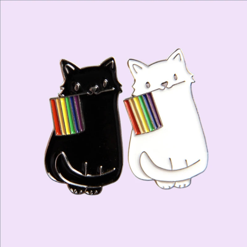 Dieser einzigartige Pin zeigt eine schwarze und eine weisse Katze, die stolz eine LGBTQI+-Regenbogenflagge im Mund tragen. Das Design vereint die kraftvolle Symbolik der Regenbogenflagge mit der geheimnisvollen Eleganz der Katze, wodurch ein ausdrucksstarkes Accessoire entsteht. Perfekt, um an Jacken, Taschen oder Rucksaecken ein Statement für Vielfalt und Akzeptanz zu setzen!