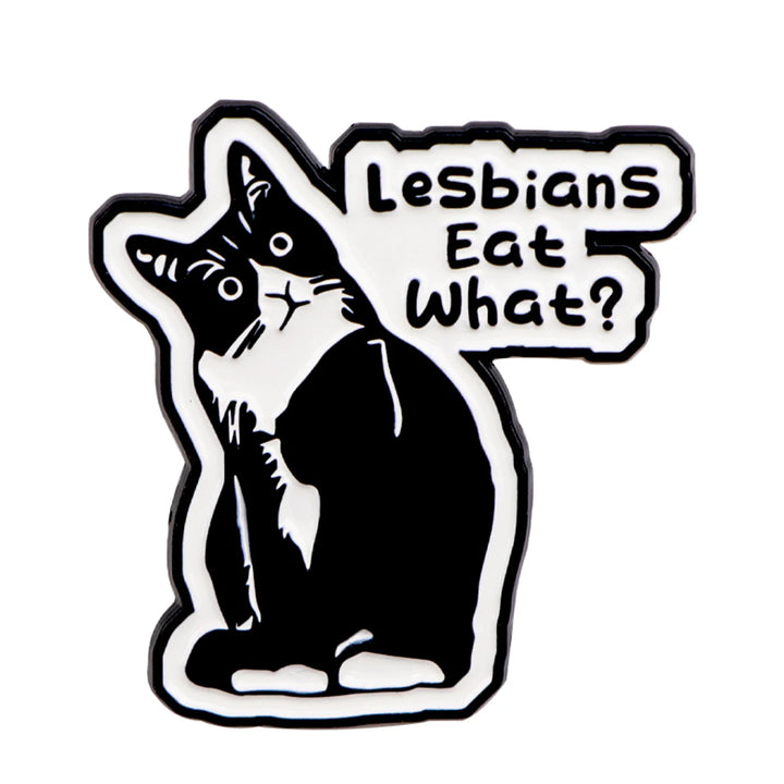 Der Pin zeigt eine detaillierte Katze mit feinen Konturen und der humorvollen Aufschrift „Lesbian eat what?“. Die Oberflaeche ist glatt und glaenzend, was das Katzenmotiv klar und gut sichtbar macht. Der Pin besteht aus einer schwarzen, robusten Metall-Zink-Legierung und hat einen sicheren Verschluss auf der Rückseite, um ihn problemlos an Kleidung oder Accessoires zu befestigen. Ein kleines, stilvolles Accessoire, das Humor und Stil vereint.