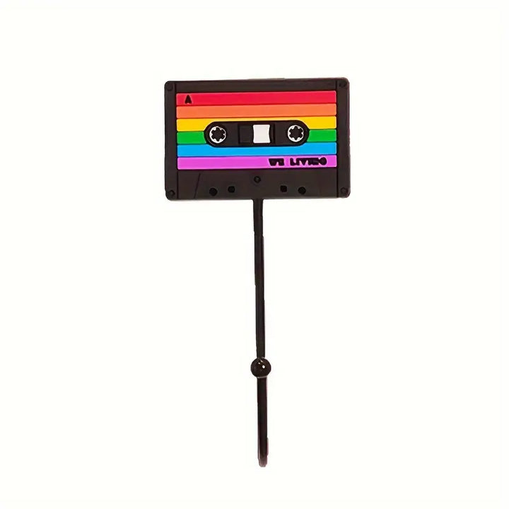 Dieser Haken ist als klassische Kassette gestaltet und zeigt alle typischen Merkmale, wie die Spulen und das Etikettenfeld. Die Kassettenform ist in bunten Regenbogenfarben gehalten, die fuer eine positive, froehliche Atmosphaere sorgen. Perfekt, um deinem Raum eine nostalgische Note zu verleihen.